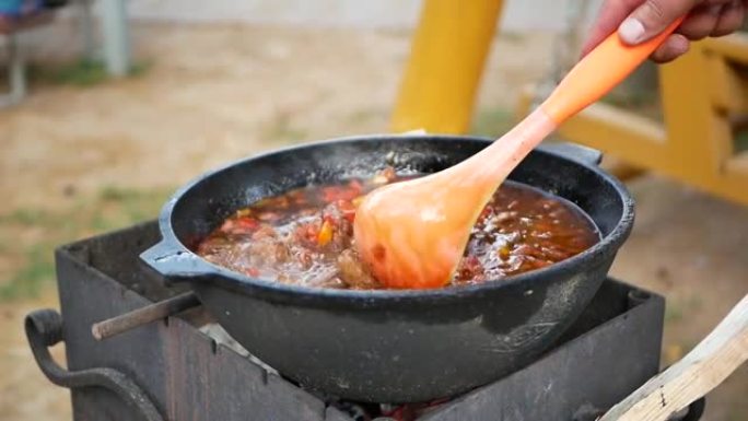 室外大型铸铁大锅里的Hurpa汤。用手搅拌汤