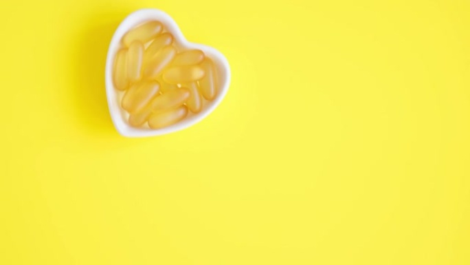 欧米茄3胶囊在黄色背景的心形盘子。鱼油软胶囊。顶视图