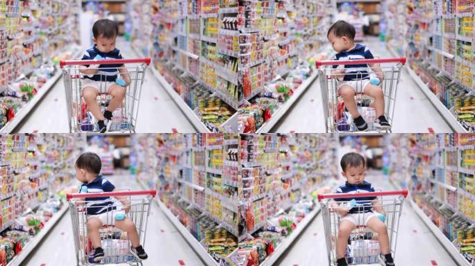 亚洲男婴坐在购物车里买杂货