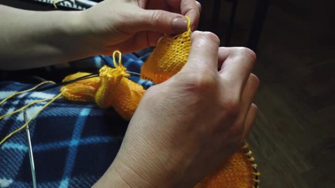 女式手工针织羊毛夹克，配有织针。俯视图，手和编织的特写。