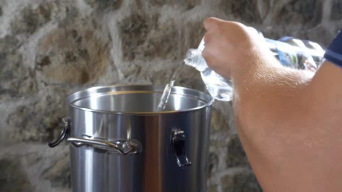 精酿啤酒制造商的手在锅里装满水