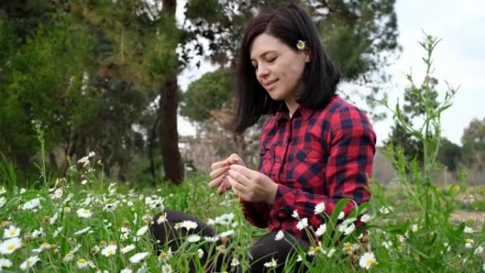 女孩从洋甘菊花中摘下花瓣。他爱我而不是占卜。