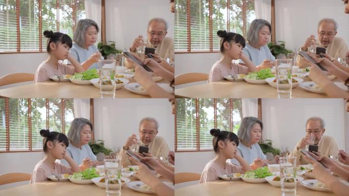 沮丧的女儿坐在午餐桌上，看着上瘾的父母和祖父母在吃早餐时使用智能手机。忽视家人不注意小孩。糟糕的家庭