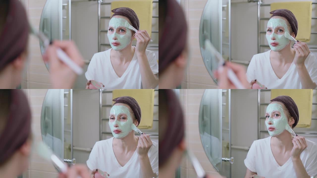 女人在浴室spba上涂化妆品面膜，看着镜子。照顾女孩