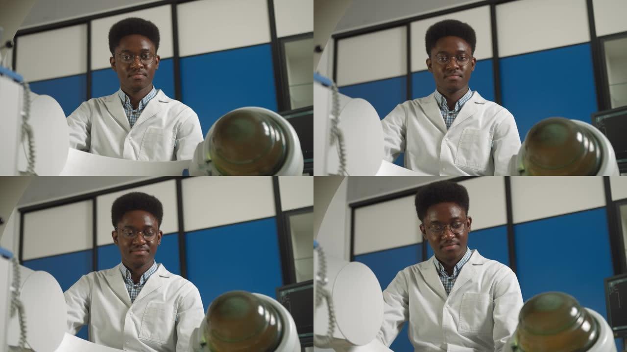 年轻自信的非洲医生穿着白色制服的底视图，与现代碎石机设备一起治疗肾结石。无创体外休克波碎石术