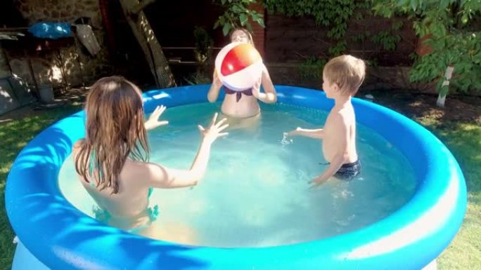 有趣的小男孩在房子后院花园的游泳池里玩充气彩色球。幸福快乐的家庭暑假和假期的概念