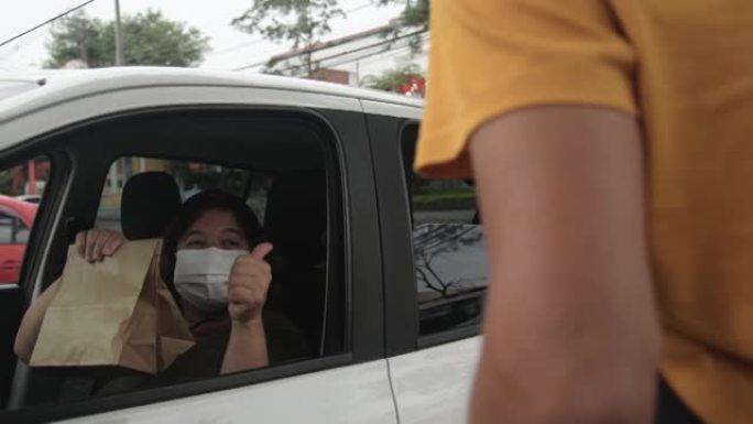 成熟的女人从车里挑选餐馆的食物。