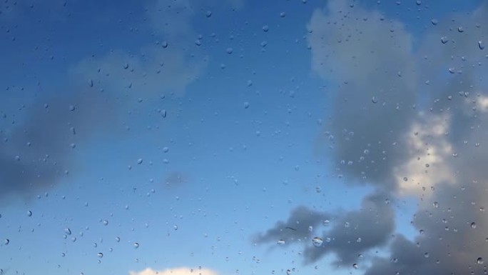 云层经过玻璃窗后的时间流逝，玻璃窗上有新鲜的雨滴