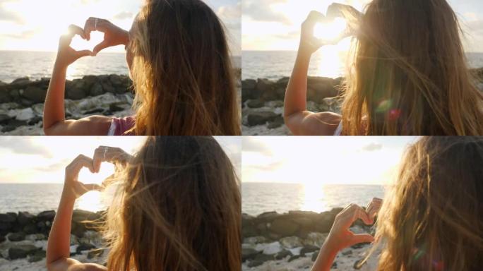 女人在日出时做一个心形的指框。