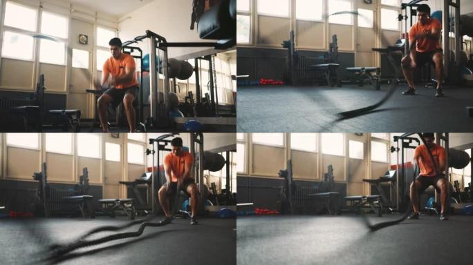 一名运动男子在健身房用战斗绳索锻炼