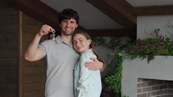 幸福的年轻夫妇自豪地展示了他们新房子的钥匙
