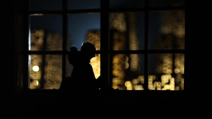 从玩具屋的窗户可以看到夜晚微型城市的美丽景色。窗户上的浪漫情侣。艺术品桌子装饰与手工逼真的玩具屋。选