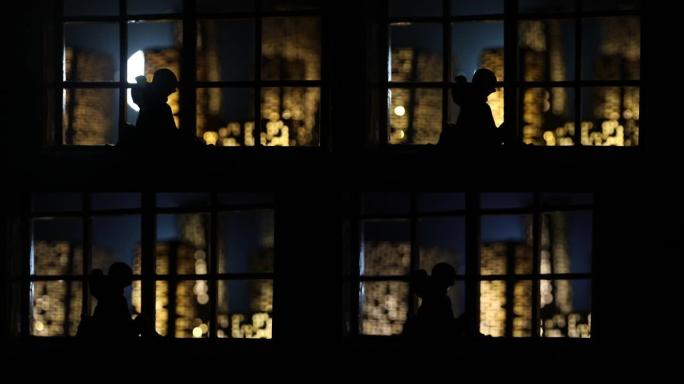 从玩具屋的窗户可以看到夜晚微型城市的美丽景色。窗户上的浪漫情侣。艺术品桌子装饰与手工逼真的玩具屋。选
