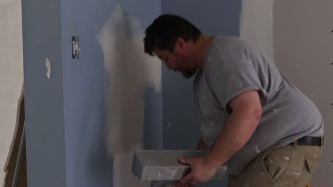 用抹灰工男子粉刷墙和腻子石膏对齐墙的公寓装修工程