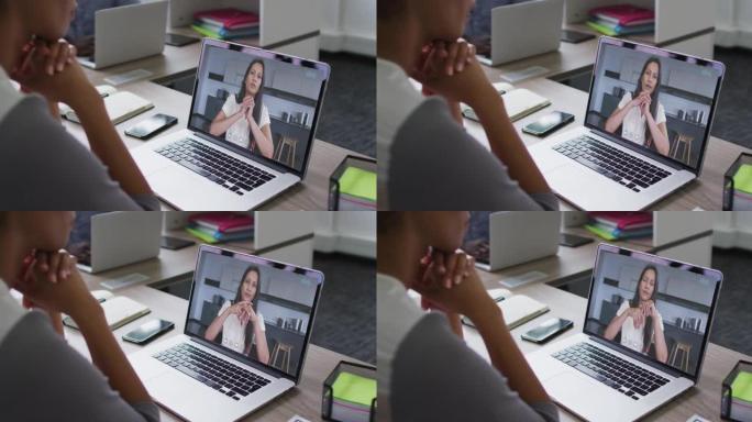 非裔美国妇女的中间部分在办公室的笔记本电脑上与女同事进行视频通话