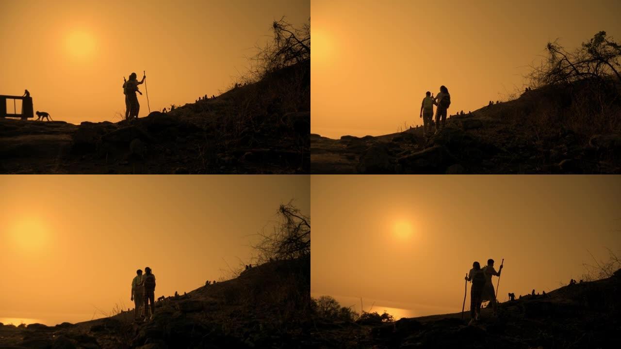 亚洲背包客儿童在山顶上行走的剪影与早晨的日出，生活方式的概念。