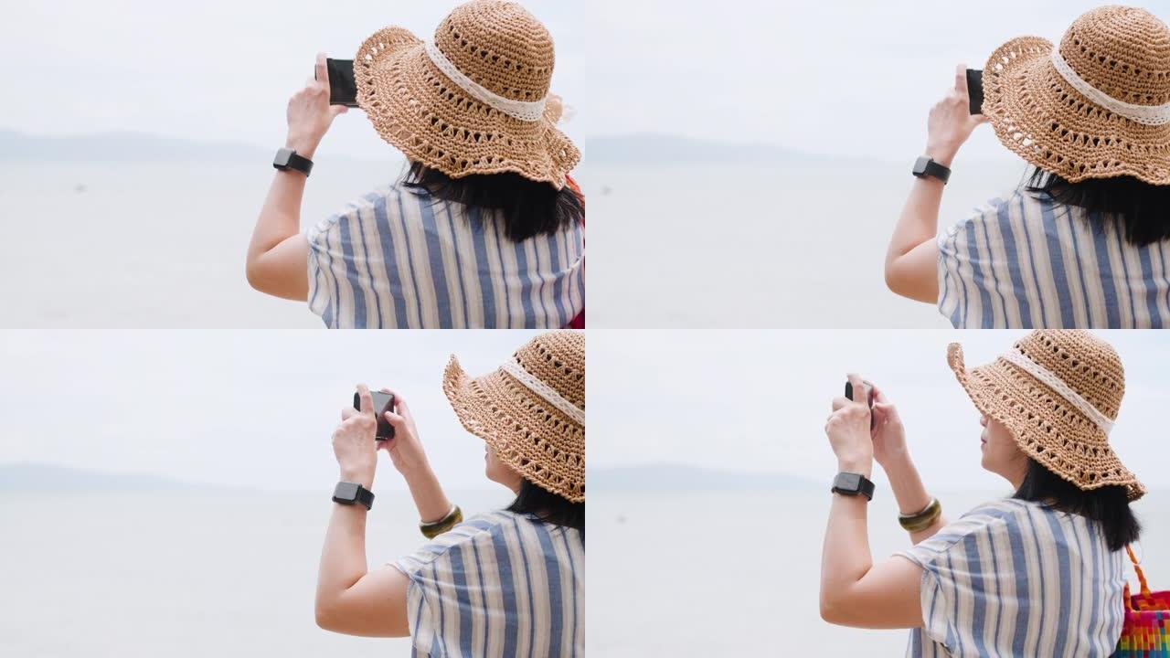 亚洲妇女在暑假期间使用手机在海滩上拍照。独自旅行