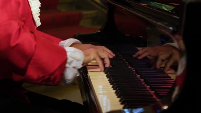 一名男子钢琴家，穿着18世纪贵族的衣服，在钢琴上演奏沃尔夫冈·阿马德乌斯·莫扎特的回旋曲。