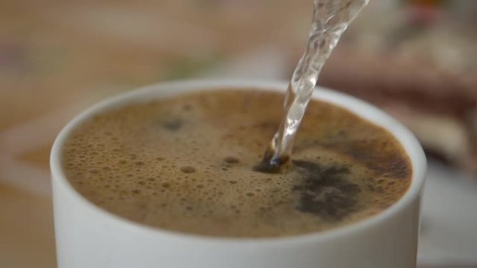 将热水倒入白杯巧克力中。新鲜的早晨倒在咖啡上特写。慢动作。白色杯子里的牛奶巧克力。从水壶里倒热水，做