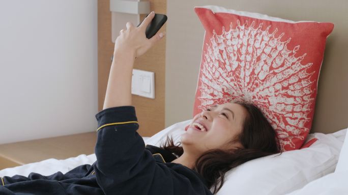 美女开心躺在床上玩手机视频聊天