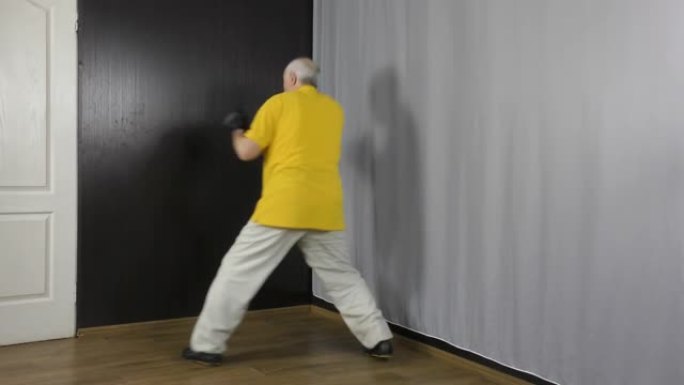 一位老人运动员，手上有黑色护垫，在架子和拳打中训练运动。