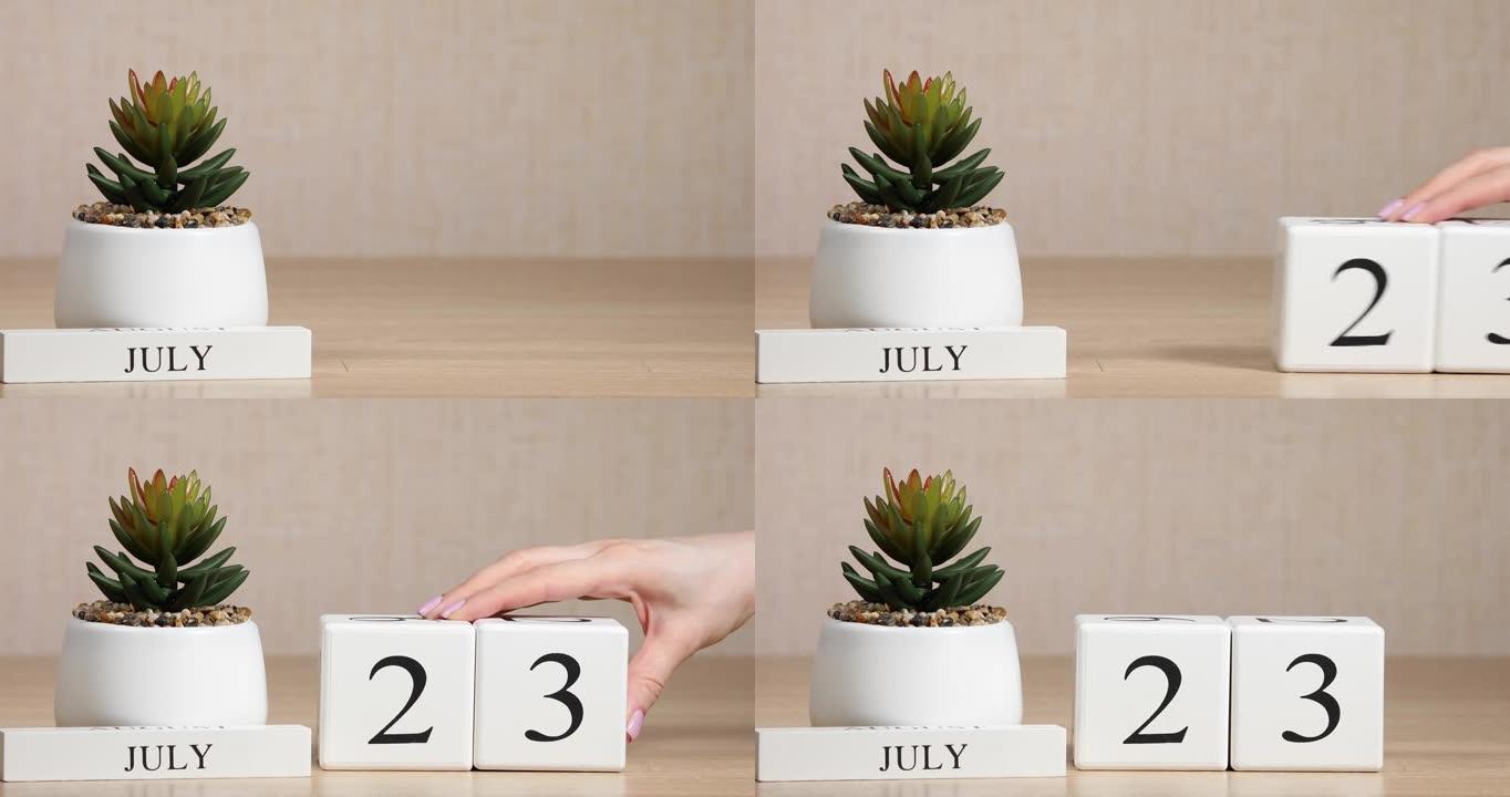 木制日历对7月23日来说是一个重要的事件，女人的手在日历上设置日期。夏季。