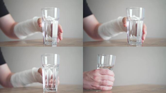 一个骨折的人试图拿一杯水。残疾。手腕上的绷带