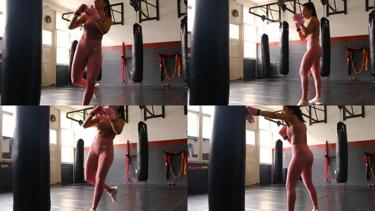 年轻的女跆拳道运动员在健身房踢一个沉重的包