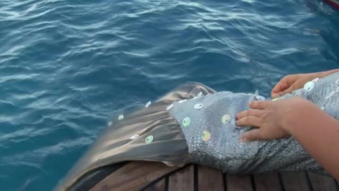 免费潜水员模特在红海附近的船上穿着美人鱼服装。