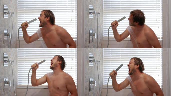 快乐的年轻人唱歌洗澡。微笑的大胡子肌肉男人在温水下洗衣服，听音乐，享受浴室里的卫生习惯。