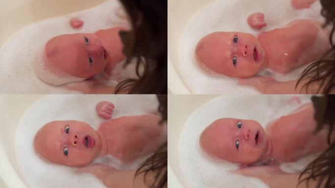 母亲在婴儿洗澡时给新生男婴洗澡，面对1个月大的新生男婴特写镜头。