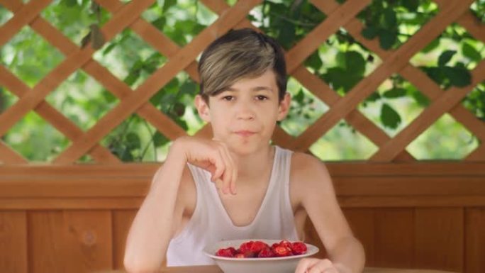 男孩坐在户外享受草莓