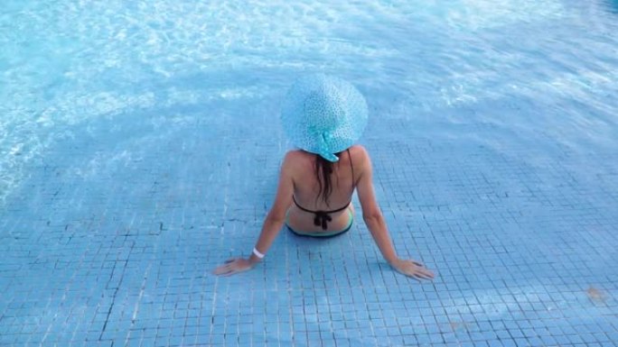 戴着蓝帽子的快乐年轻女子坐在酒店的游泳池里。埃及真正的休息。海上度假胜地。1920x1080中的视频