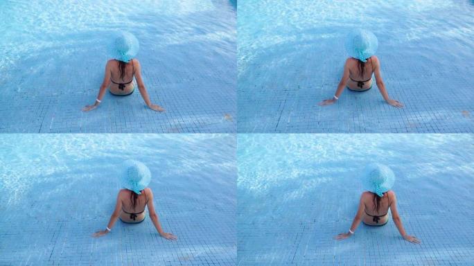 戴着蓝帽子的快乐年轻女子坐在酒店的游泳池里。埃及真正的休息。海上度假胜地。1920x1080中的视频
