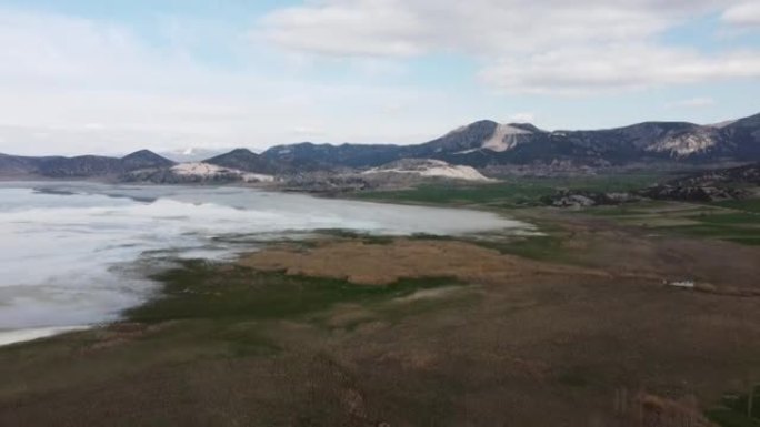 无人机将摄像机从大湖和山景向后倾斜。