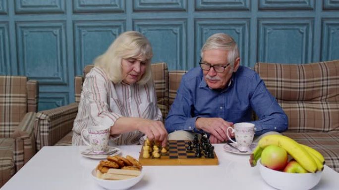 退休的高级夫妇在现代客厅休息室里聊天喝茶，下棋