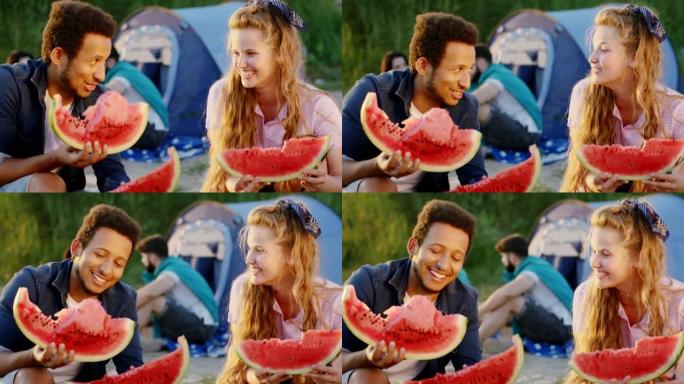具有超凡魅力的多种族朋友在野餐时聊天，微笑着拿着大块西瓜