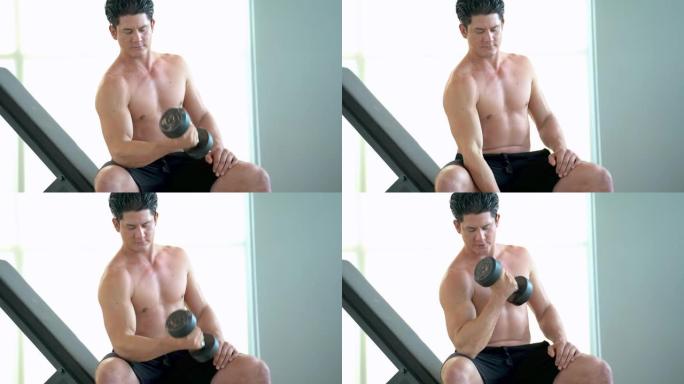 肌肉男在健身房的长凳上举起哑铃。男人赤裸上身做重量训练以保持身体稳定。健康生活方式的活动。男子举起并