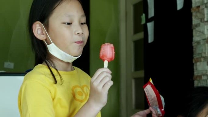 快乐的亚洲儿童吃冰淇淋，在家坐在沙发上一起玩耍，生活方式理念。