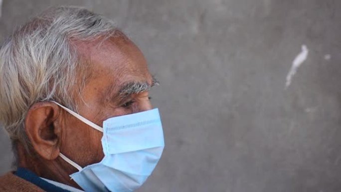 在电晕病毒大流行期间戴着防护口罩的印度老人的侧面肖像。老年护理的概念。背景中有复制空间
