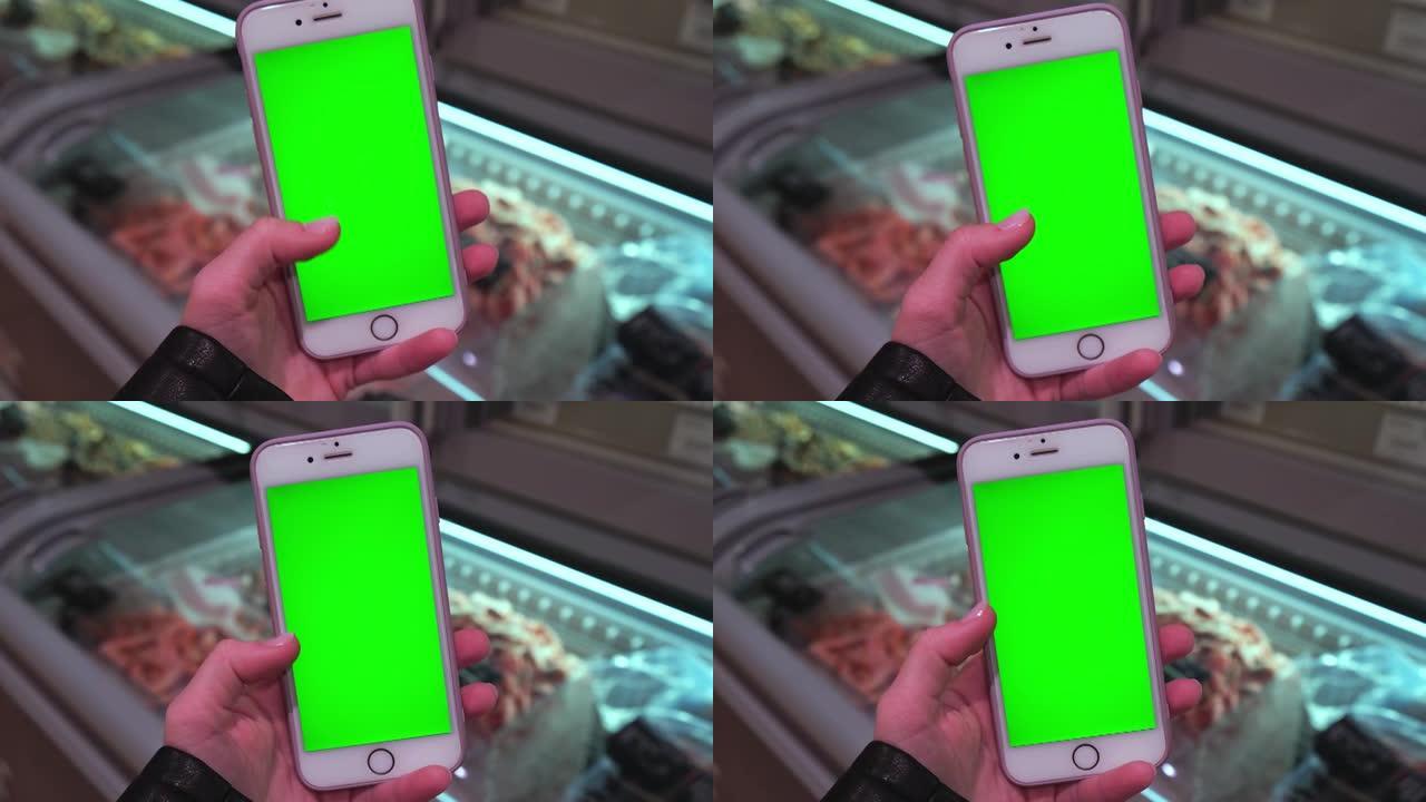 色度键。女人的特写镜头在杂货店拿着绿屏智能手机。购物中心。百货公司。商城。网上购物