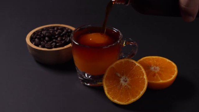 冷煮咖啡倒入玻璃中，冰球由橙汁制成，黑色背景。
