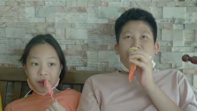 快乐的亚洲儿童在沙发上一起吃冰淇淋，生活方式概念。
