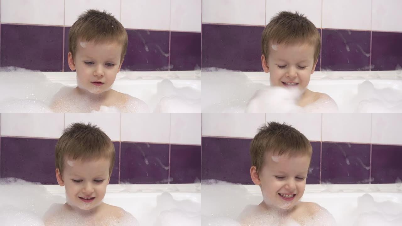 一个快乐微笑的小男孩的特写镜头，浴缸里有很多泡沫。他拍手泡沫。