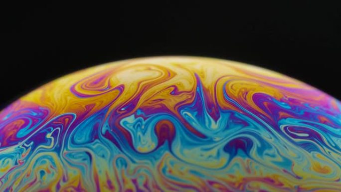 半圆一个肥皂泡表面五彩的运动隔离在黑色背景上。鲜艳的彩虹色在怪异和奇怪的图案。特写。慢动作