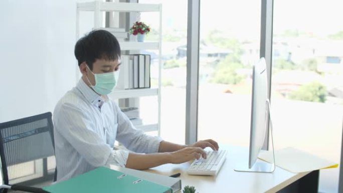 办公室工作的新常态，年轻商人使用防护面罩和丙烯酸隔墙