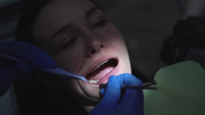 牙医的女士嘴的特写镜头用牙科灯照亮。牙医椅上张开嘴的女性病人脸。牙科诊所的专业牙科修复。高质量