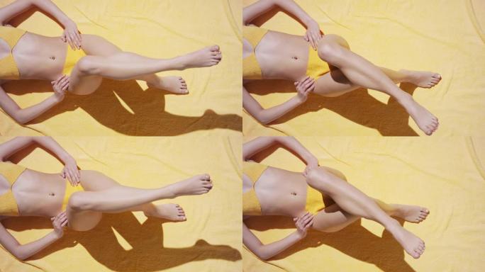 躺在毯子上的泳装模特移动双腿晒日光浴