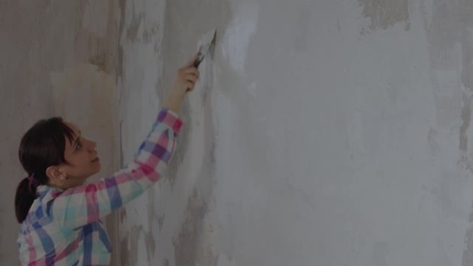一名妇女在修理房屋时在墙壁上放油灰。工作过程中，女工放油灰解决方案。用你自己的手修理。文本的位置