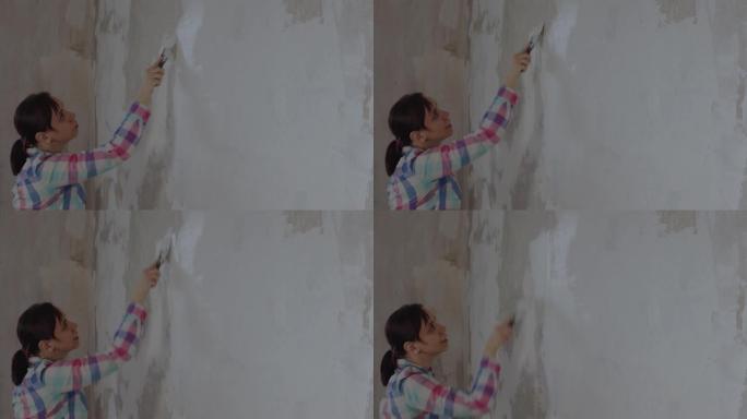 一名妇女在修理房屋时在墙壁上放油灰。工作过程中，女工放油灰解决方案。用你自己的手修理。文本的位置